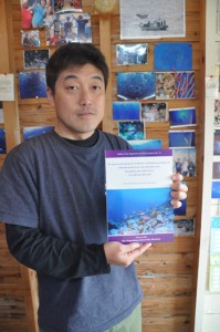 鹿児島大学総合研究博物館と共同出版した「沖永良部島の魚類目録」を手にする上原さん＝２日、和泊町  