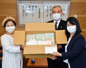 絹地でできた手作りマスクを寄贈したアーダンの西会長（左）＝３０日、奄美市役所