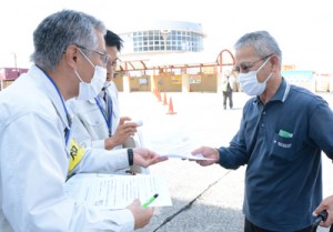 来島者へ活動自粛を呼び掛けるチラシを配る知名町職員（手前左）＝１５日、和泊港