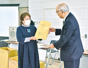 竹田泰典町長（右）から手作りマスクを受け取る隈元区長＝２７日、龍郷町役場