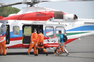 県の防災ヘリに沖永良部島内の濃厚接触者の検体を運び込む保健所職員（右）＝２日午後１時２０分ごろ、和泊町の沖永良部空港  