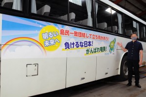 新型コロナウイルスに立ち向かう人たちへの応援メッセージを掲載したしまバスを紹介する勝村社長代理＝２７日、奄美市