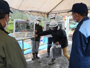 大美川の川底掘削、護岸等工事の概要などを説明する県大島支庁職員＝２２日、龍郷町