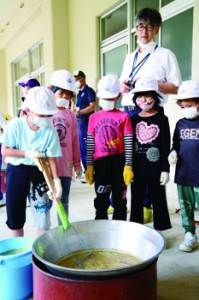 石灰を加えたキビ汁のあく取りに挑戦する児童＝４日、大和村の名音小学校