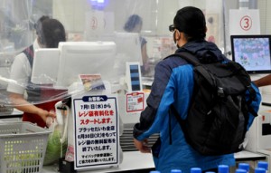 レジ前に案内を張り、１日からレジ袋が有料化されることを周知している店舗＝２７日、奄美市名瀬