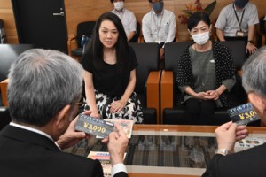 朝山奄美市長（左手前）にチケットの説明をする屋仁川ママの会の会員＝１日、市役所