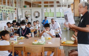 県産和牛を味わいながら、生産者から畜産の説明を聞く児童ら＝１０日、和泊町の大城小学校 