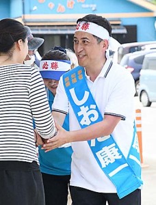 選挙期間中、徳之島で有権者と笑顔で握手を交わす次期知事の塩田康一さん＝６月２９日、伊仙町