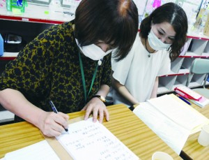 学級ＰＴＡ会合で、要約筆記者（左）の筆記で、話し合われている内容を確認する大野さん＝１日、奄美市の小学校