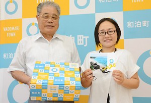 和泊町出身の学生に届ける応援物資「わらんちゃ応援ギフト」を持つ伊地知実利町長（左）ら＝１４日、同町