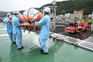 感染者（想定）をはしご車のバスケットから巡視船の甲板に搬入する奄美海保職員＝１５日、奄美市の名瀬港観光船バース