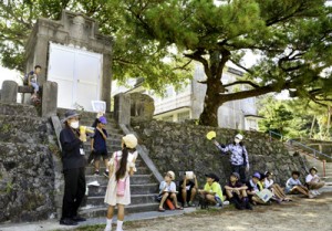 古仁屋小学校敷地内の旧奉安殿前で説明を受ける参加者ら＝１５日、瀬戸内町古仁屋