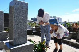 墓前で手を合わせて先祖の霊を迎える住民＝１３日、徳之島町亀津