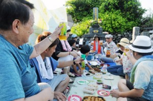 墓前で酒や料理を囲んで語り合い、先祖の霊を慰める一族＝１５日夕、知名町瀬利覚