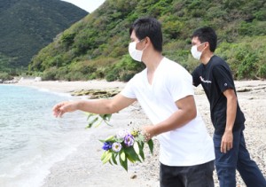 行方不明の乗組員４０人の発見を祈り、海へ献花するサリーノさん（奥）とロザレスさん＝１７日、瀬戸内町西古見の海岸