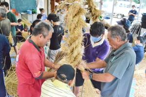 共同作業で大綱を編み込んでいく参加者＝２０日、与論町の城自治公民館