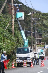 電線や電柱の点検、補修を行う業者＝７日午後１時半ごろ、奄美市笠利町の県道