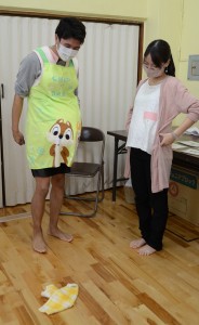 妊婦ジャケットを着たまま、どうハンカチを拾おうかと思案する参加者＝１９日、奄美市名瀬