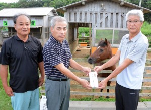坂井会長（左から２人目）から寄付金を受け取る髙野代表理事＝１９日、知名町の余多ふれ
