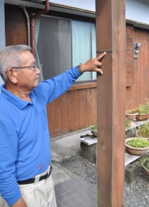 ２０１１年９月の豪雨災害を忘れないよう、柱に付けた浸水の高さの印を指さす山口さん＝１０日、龍郷町下戸口