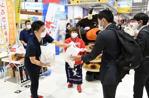 来島者へ奄美黒糖焼酎や特産品などをプレゼントしてＰＲした酒造メーカーと徳之島町の職員＝３１日、天城町の徳之島空港