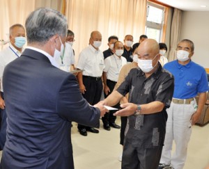 伊集院村長（左）から助成金を受け取る村区長会の中井会長＝２日、大和村防災センター 