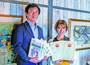 日本地域情報コンテンツ大賞の観光部門で優秀賞を受賞したフリーペーパー「ほっとくの」を手にするモスク・クリエイションの近藤代表取締役（左）＝提供写真