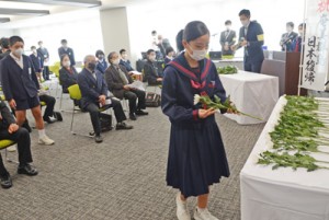 復帰運動を果たした先人に感謝を込めて献花する出席者＝２５日、奄美市名瀬