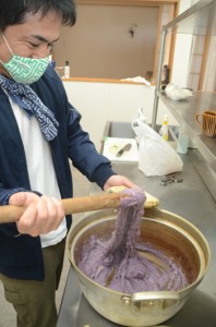 水煮したサツマイモと餅をすりこぎ棒で根気強く練りヒキャゲを作る荒波のやどりのスタッフ＝１８日、龍郷町幾里