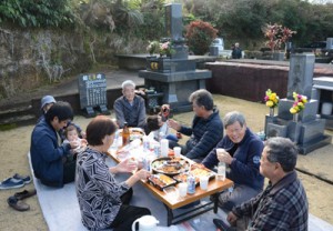 墓前で一重一瓶を囲む人たち＝１６日、知名町田皆