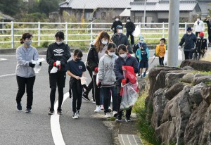 歩きながら道沿いのごみを回収する参加者＝２４日、天城町松原