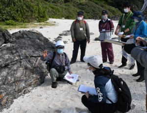 成尾さん（左）の説明を受け、地質の成り立ちについて学ぶ参加者＝２１日、徳之島町金見