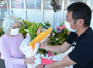 沖永良部島産の花束をプレゼントする知名町農業青年クラブのメンバー（右）＝１４日、知名町