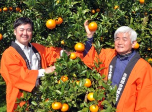 たわわに実ったタンカンを手に笑顔を見せる園主の平井さん親子＝１日、奄美市名瀬