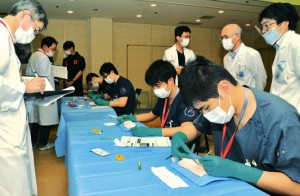 先輩医師が採点する中、外科技術を競う研修医たち＝３日、奄美市名瀬