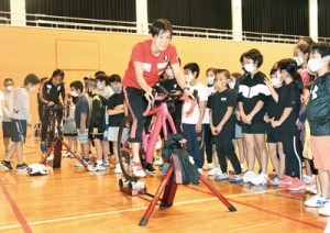 リズムに合わせてバイクをこぐ練習方法を紹介する井出さん（中央）と蔵本さん＝７日、伊仙町伊仙