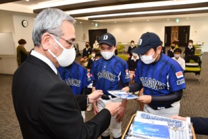 朝山市長（手前）からベイスターズのプレゼントを受け取る児童ら＝３日、奄美市役所