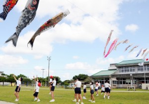 風に乗って泳ぐこいのぼりを楽しむ児童ら＝２１日、知名町