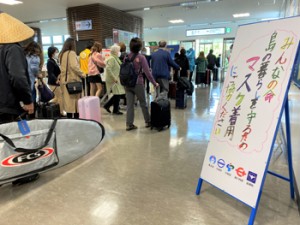  空の玄関口・奄美空港。到着ロビーにはメッセージ看板が設置され、来島者に新型コロナ感染防止のためのマスク着用を呼び掛けている＝１８日、奄美市笠利町