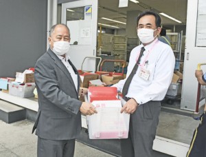 「ささえ愛クーポン券」を古仁屋郵便局に届けた鎌田町長（左）＝２３日、瀬戸内町古仁屋