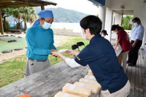 役場職員から地域商品券を受け取る住民（左）＝２６日、大和村国直