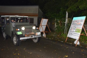 案内板をみながら野生生物の観察ルールなどを説明するガイドとツアー客＝４月２９日、奄美市住用町